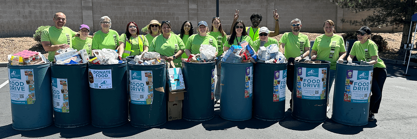 volunteers in green shirts standing in front of shred day bins