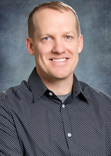 Jake Jackson headshot wearing a gray shirt with small white polka dots