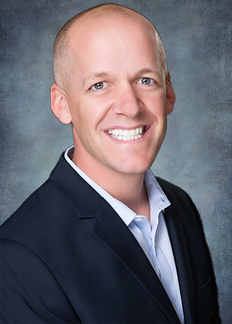 Josh Jackson headshot wearing a black blazer and a blue shirt