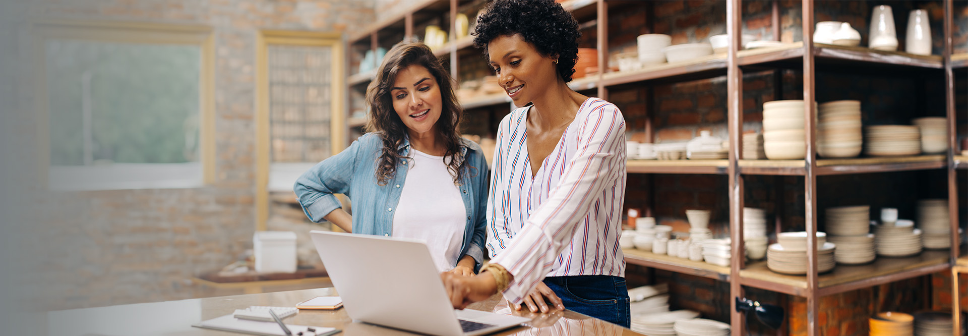 two women in a pottery business looking at a computer