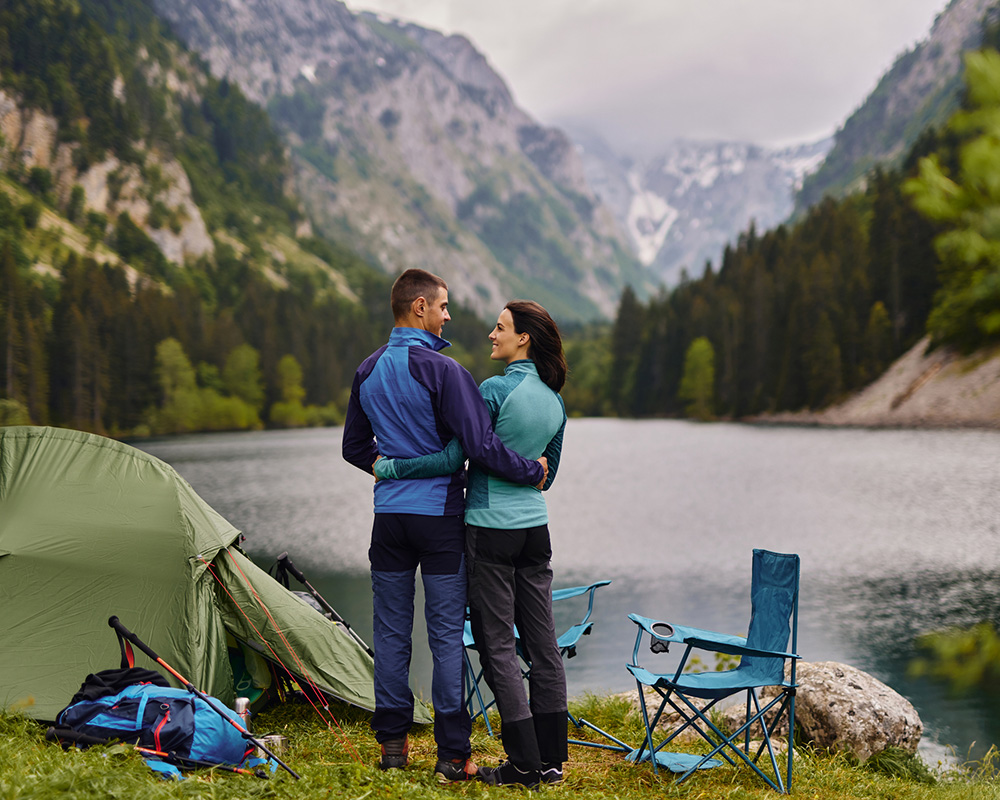 couple camping on a lake looking at each other
