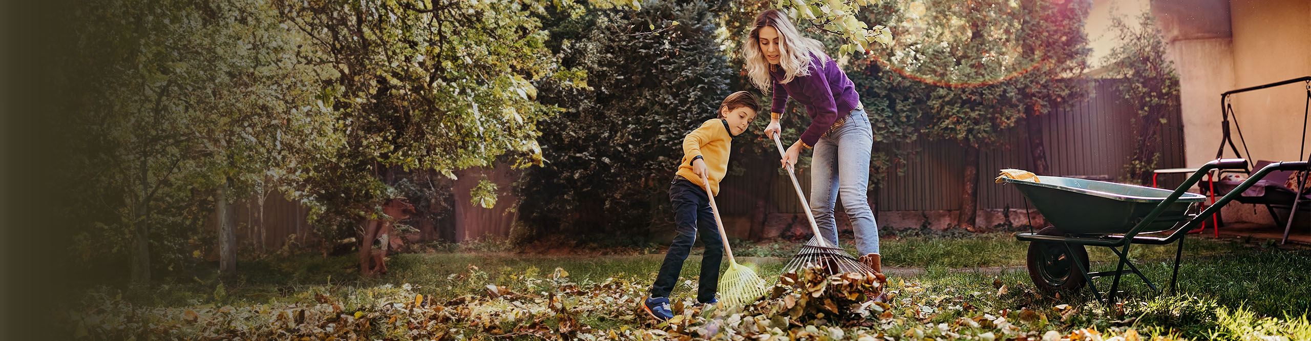 mother and son raking fall leavesin the yard